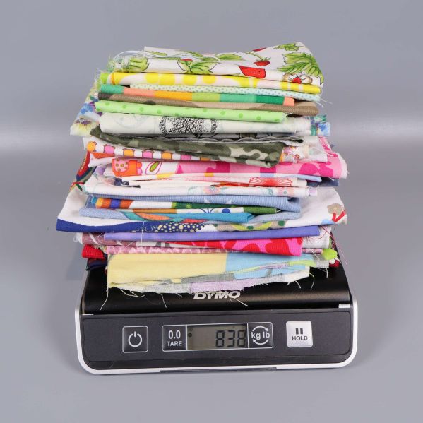 Stapel av tygbitar på våg med vikt 833 gram