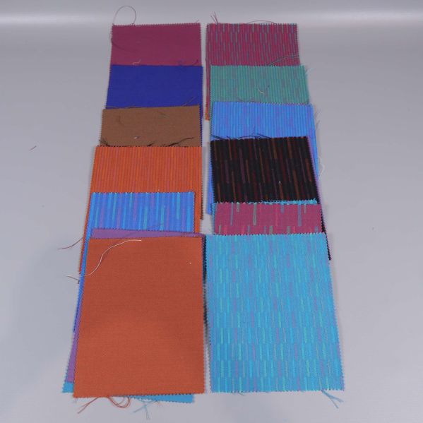 Tolv tygprover i klara nyanser och linjerade mönster uppställda på rad