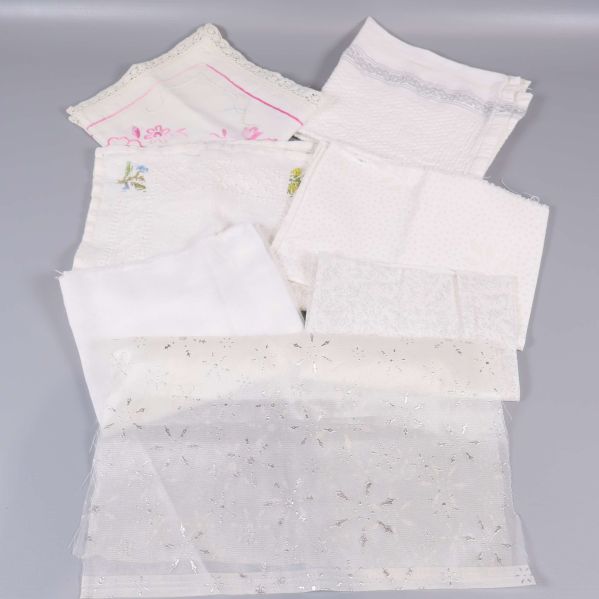 Närbild på vita och ljusa textilbitar med spets och brodyr