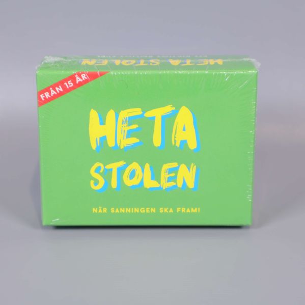 Framsidan av Heta Stolen spelkartong med färgstark text