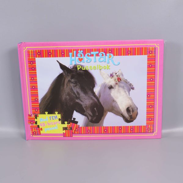 Förpackad pusselbok med hästmotiv framför grå bakgrund