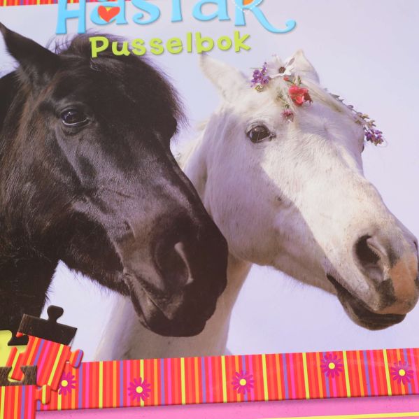Närbild på framsidan av pusselboken med två hästar