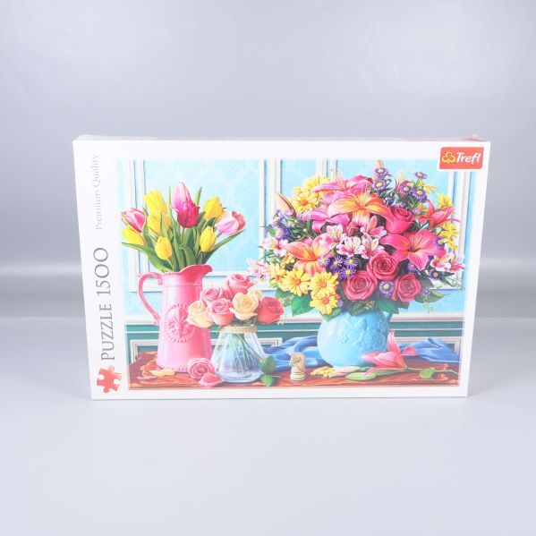 Pusselask med färgglada blommor i vaser och kanna på ett bord