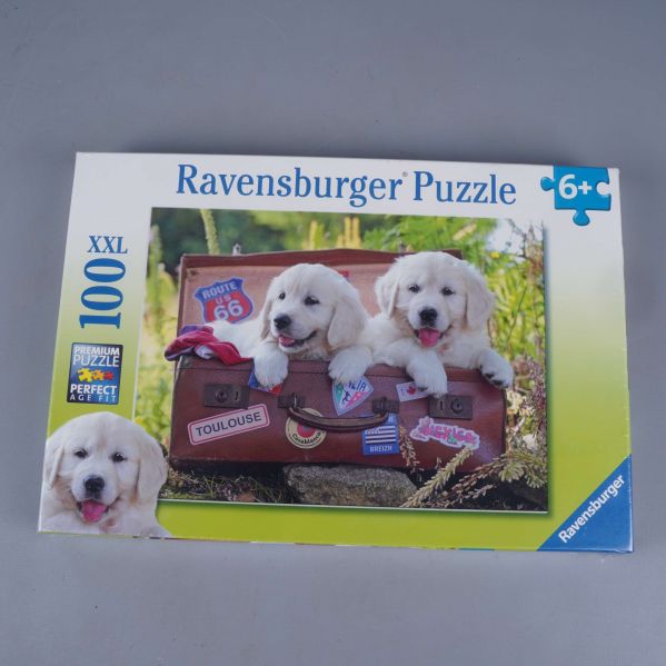 Framsidan på Ravensburger pussel med hundvalpar och resväska samt XXL och 100 bitar markerat