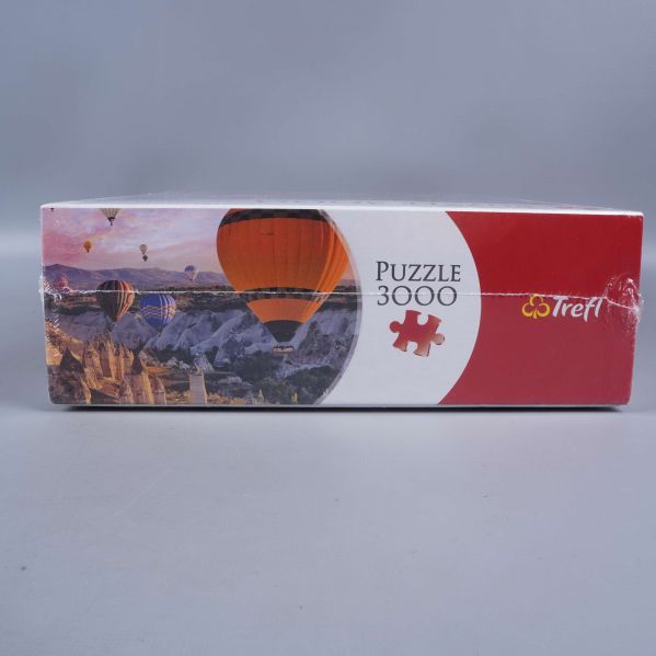 Sida av pusselask med motiv och trefl logotyp