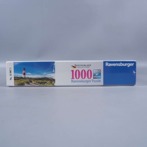 Sida av Ravensburger pusselask med fyrmotiv och logotyp