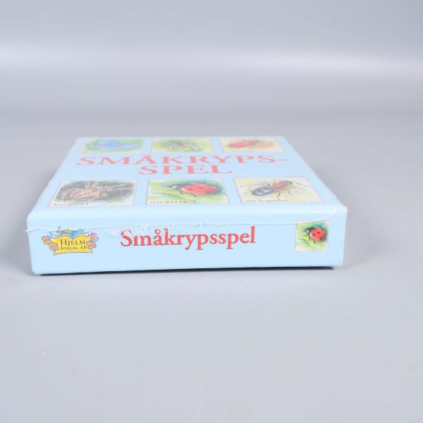 Sida av småkrypsspelets kartong med titel i röd text