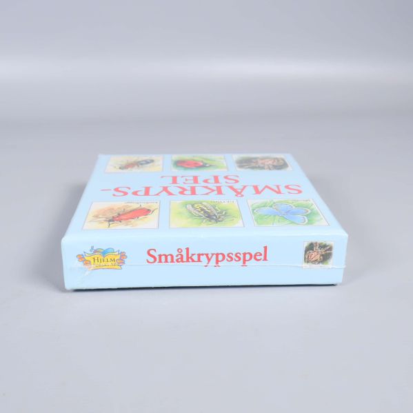 Smal sida av kartong med småkrypsspelets titel och insekt