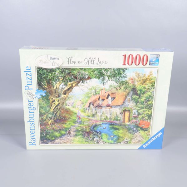 Framsidan av Ravensburger pussellåda med motiv av hus och trädgård