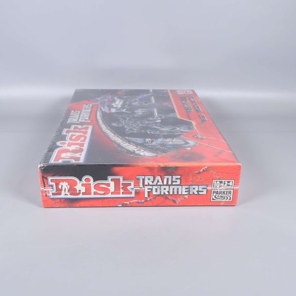 Kortsida av spelkartongen Risk Transformers visar logotyp och ålder
