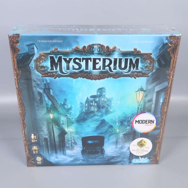 Framsidan av brädspelet Mysterium med blå mystisk design