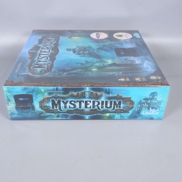 Sidan av Mysterium-lådan med logotyp och blå bakgrund