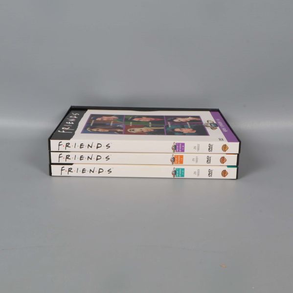 Tre staplade fodral med Friends-etiketter på ryggen