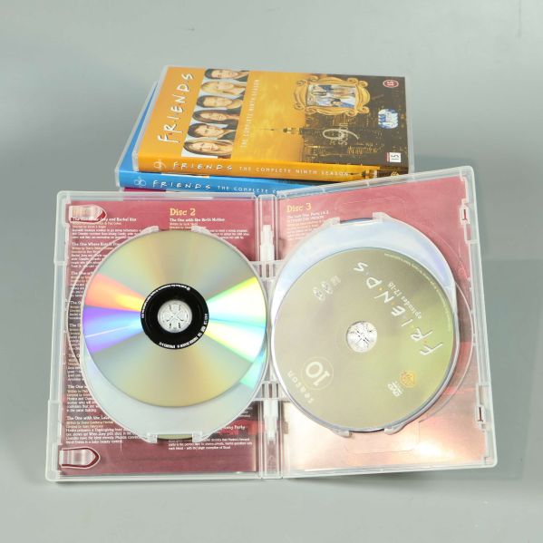 Öppnade dvd-fodral visar Friends-skivor och innehåll
