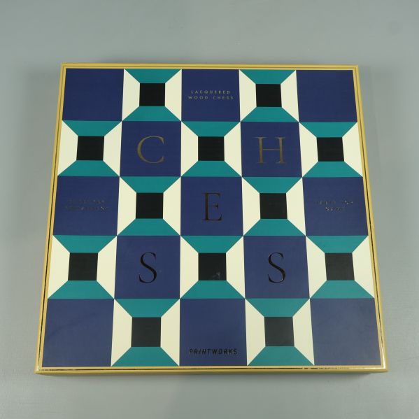 Schackspel i låda med grafiskt mönster och guldigt kant