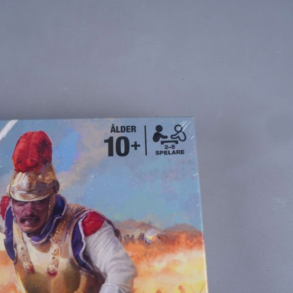 Närbild på hörn av Risk spelkartong med ålders- och spelarantalsymbol