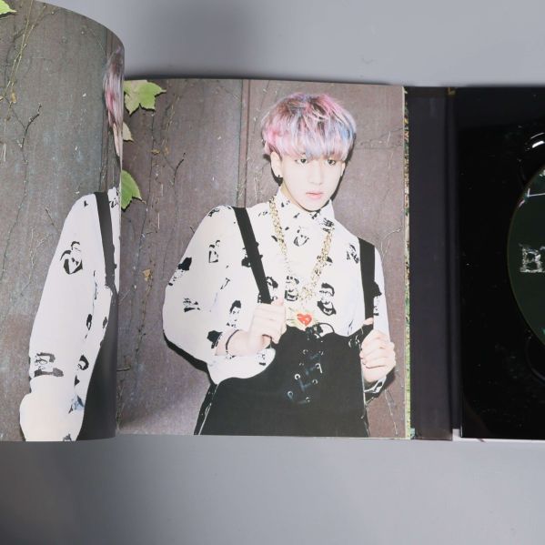 Närbild på person i vit skjorta med hängslen och halskedja