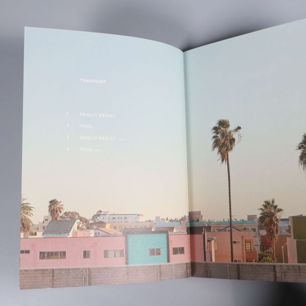 Uppslag med pastellfärgade hus, palmer och en tryckt låtlista