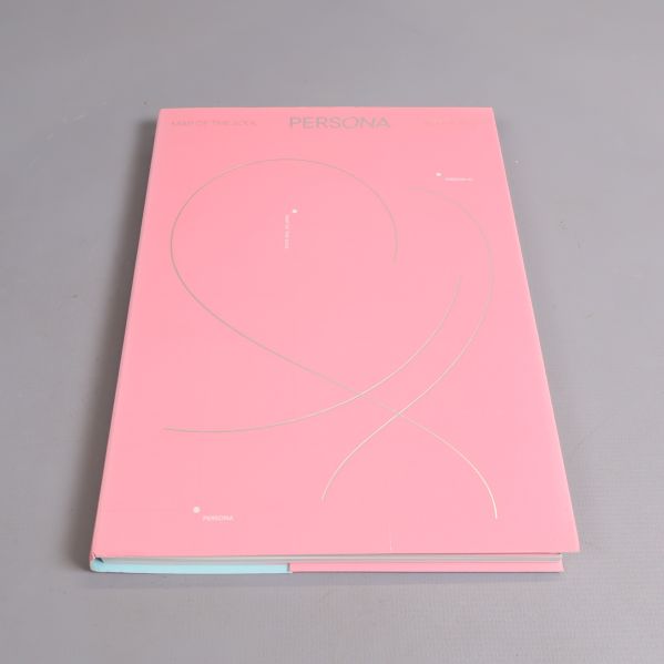 BTS-album med rosa omslag liggande på grå bakgrund