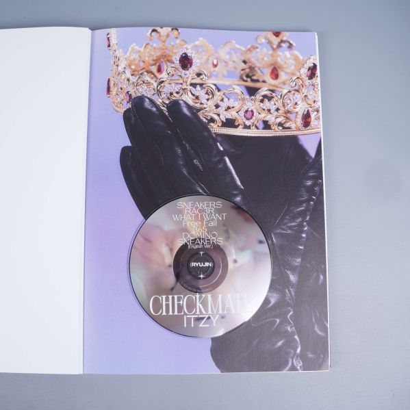 CD-skiva i fotobok med handskar och krona i bakgrund