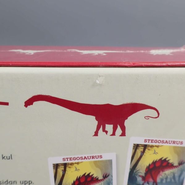 Närbild av röd dinosauriesiluett på boxen Dinosauriejakten