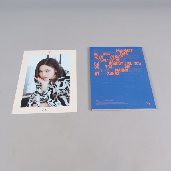 ITZY-album och fotografi av en medlem utlagda på grå yta