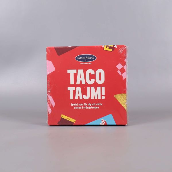 Framsidan av sällskapsspelet Taco Tajm med röd bakgrund och tacoillustration