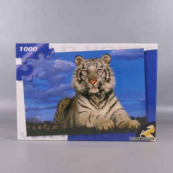 Framsida med pusselmotiv av vit tiger och blå himmel