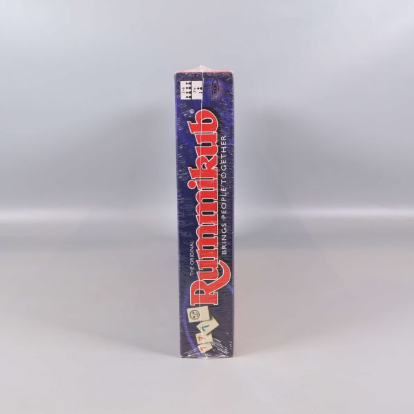 Smal sida av Rummikub-låda med logotyp och brickor