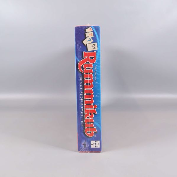 Andra smala sidan av Rummikub-låda med logotyp och brickor