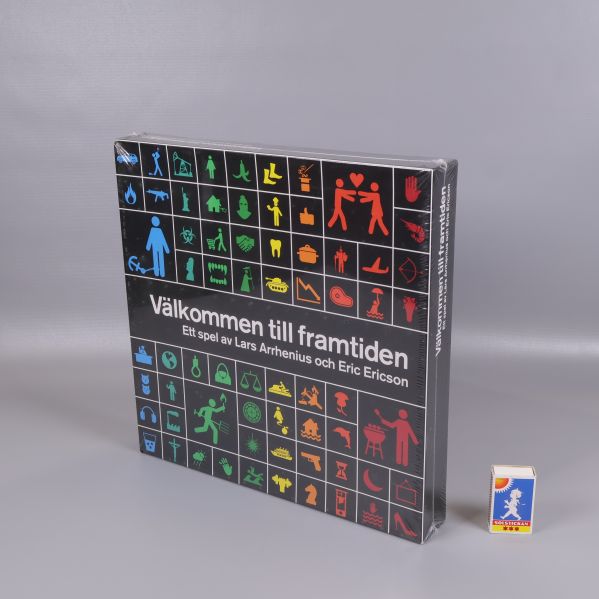 Spelförpackning i stående läge bredvid tändsticksask för storleksjämförelse
