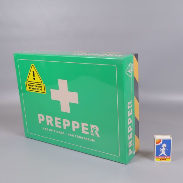 Prepper-spelask stående bredvid tändsticksask för storleksjämförelse