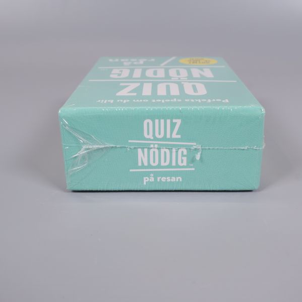 Liggande ask med Quiznödig på resan-text på sidan