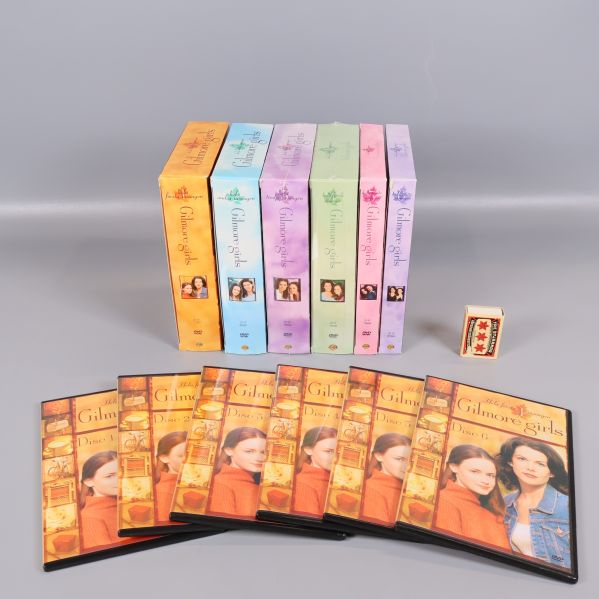Gilmore Girls boxar med flera öppnade fodral och ett tändsticksask för skala