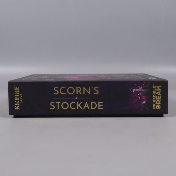Sida av brädspel med texten Scorn’s Stockade och guldfärgade detaljer
