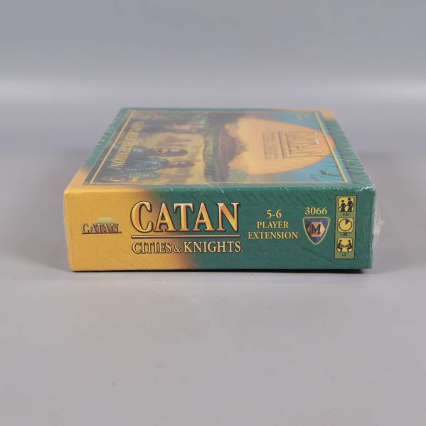 Undersidan av Catan Cities & Knights boxen med expansionstitel och symboler