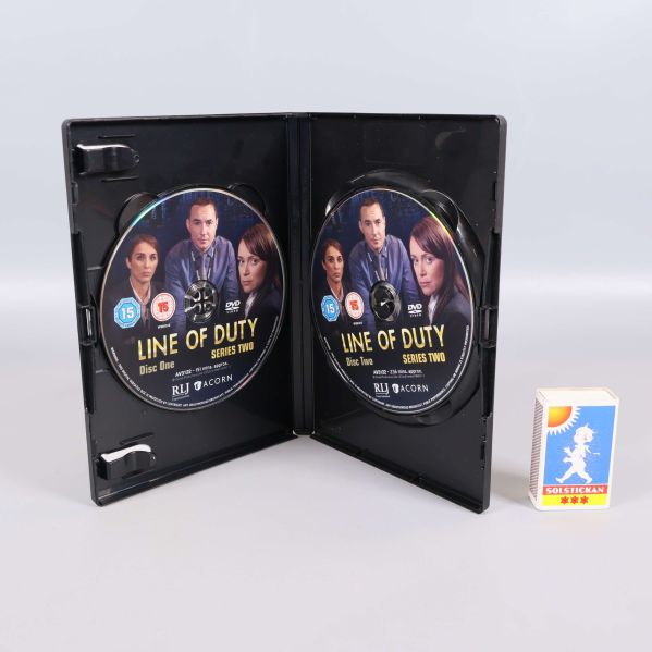 Öppen DVD-box med två Line of Duty-skivor och en tändsticksask för storleksreferens