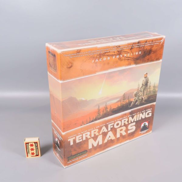 Terraforming Mars står bredvid en tändsticksask för storleksjämförelse