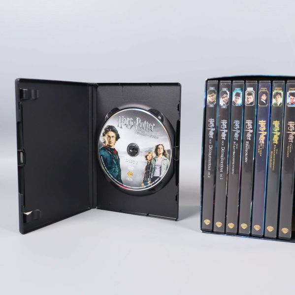 Öppen DVD-fodral med Harry Potter disc och box i bakgrunden