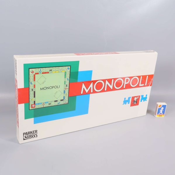 Monopoli brädspel bredvid ett mindre objekt för storleksjämförelse