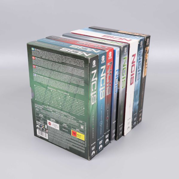 Sju DVD-boxar med NCIS säsong 1 till 8 uppställda på rad