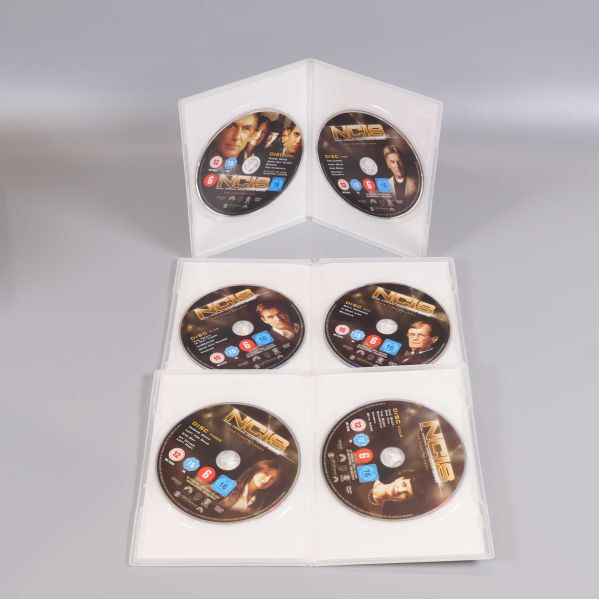Öppnade DVD-fodral med NCIS-skivor för säsong 1-8