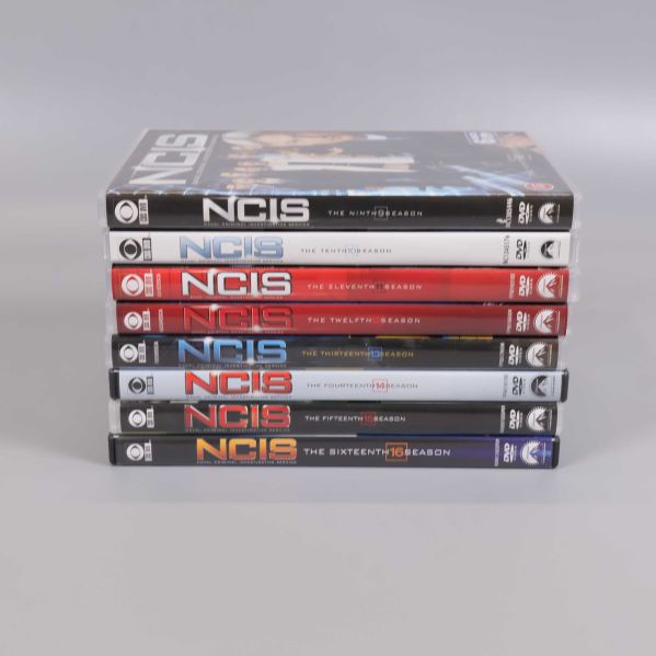 Staplade NCIS DVD-boxar med titlar och säsongsnummer på ryggen