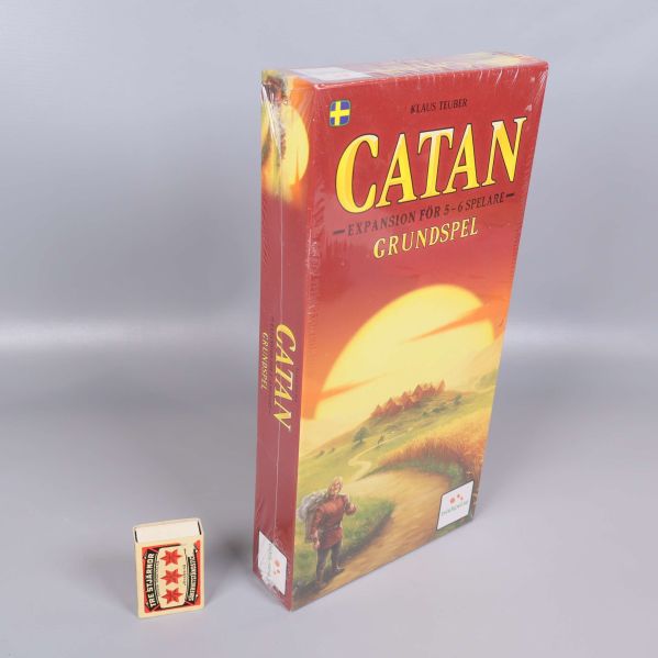 Catan grundspel stående bredvid tändsticksask för storleksjämförelse