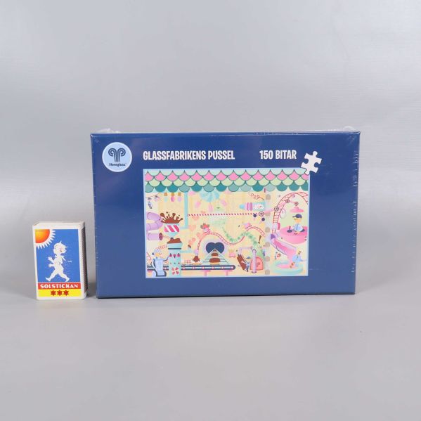 Glasfabrikens pusselask bredvid liten tändsticksask för storleksjämförelse