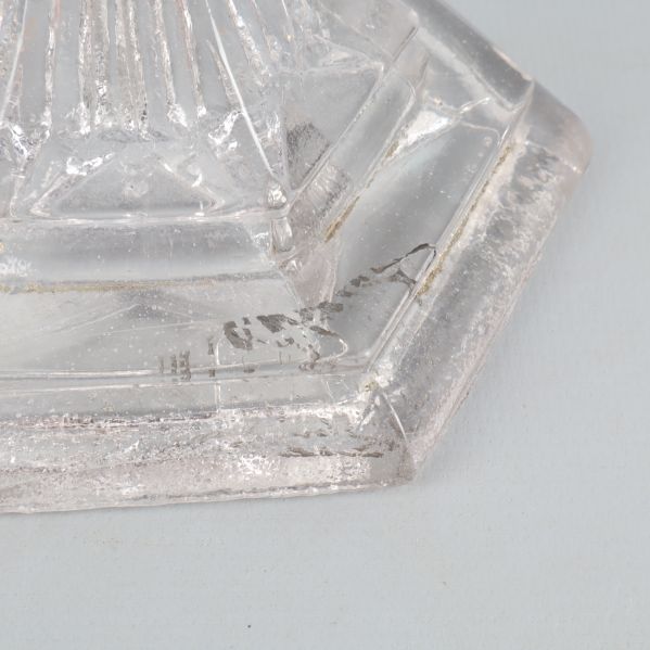 Närbild av glasskålens fot med sprickor och smuts
