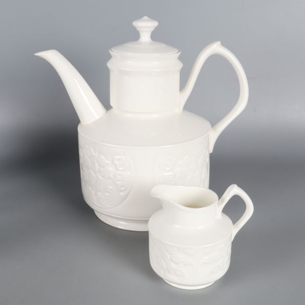 Närbild av porslinskanna och mjölkkanna i vitt