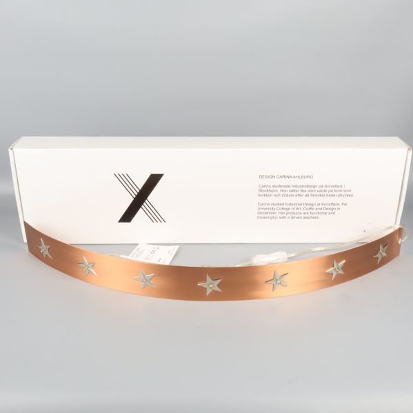 Böjd adventsljusstake med stjärnor och vit låda bakom