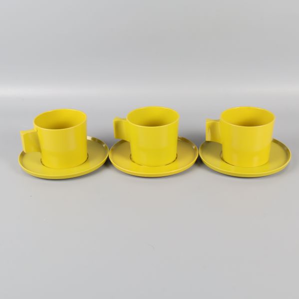 Tre gula/gröna koppar med fat i rad