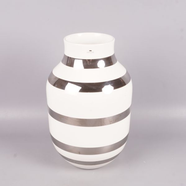 Vit och silverrandig vas upprätt på grå bakgrund